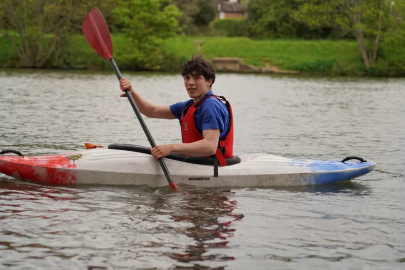 Boy in a life jacket kayaking on the River Thames at The Lensbury Leisure Club in Teddington